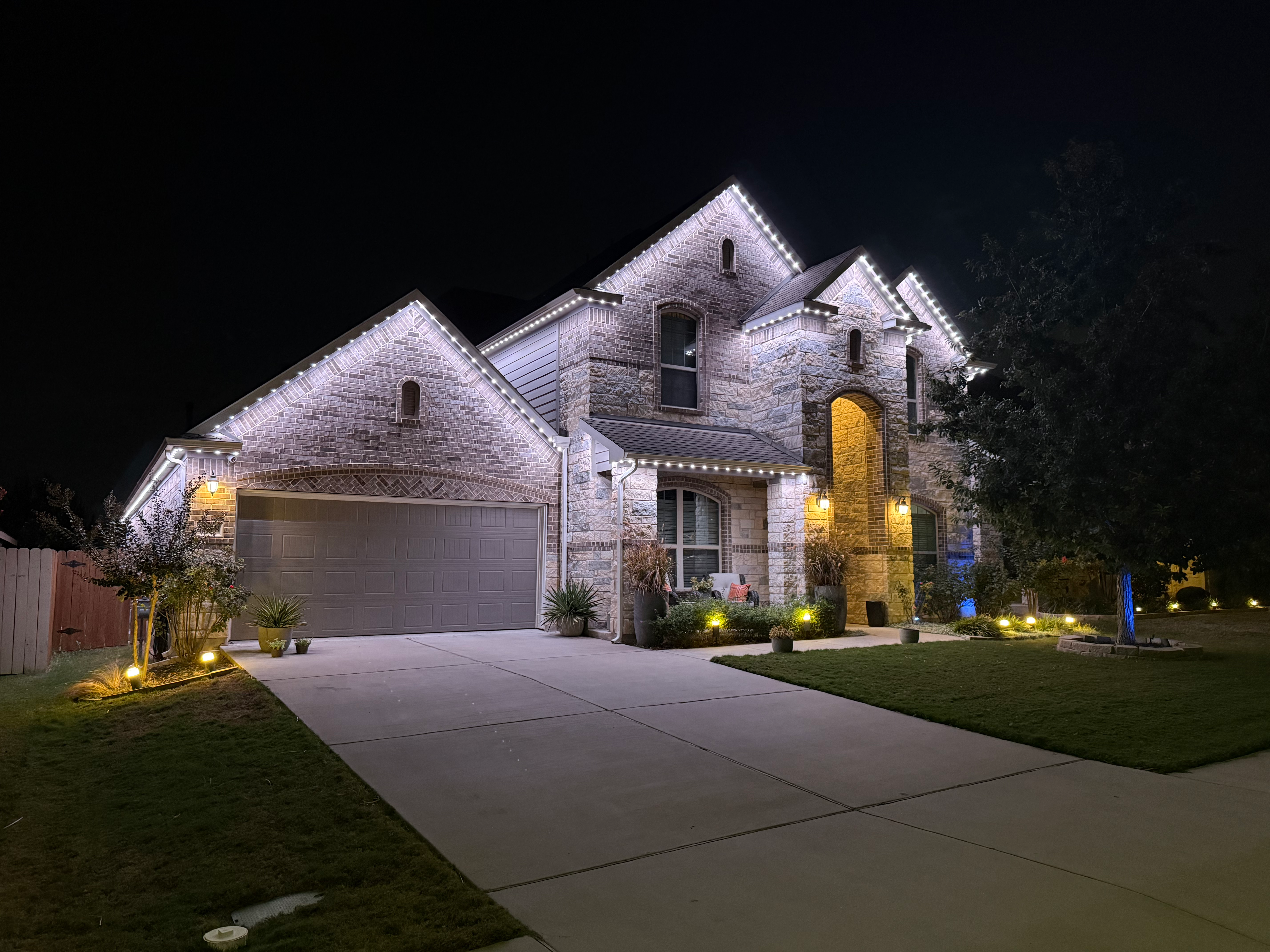 Stone home with bright white LED roofline lighting at night