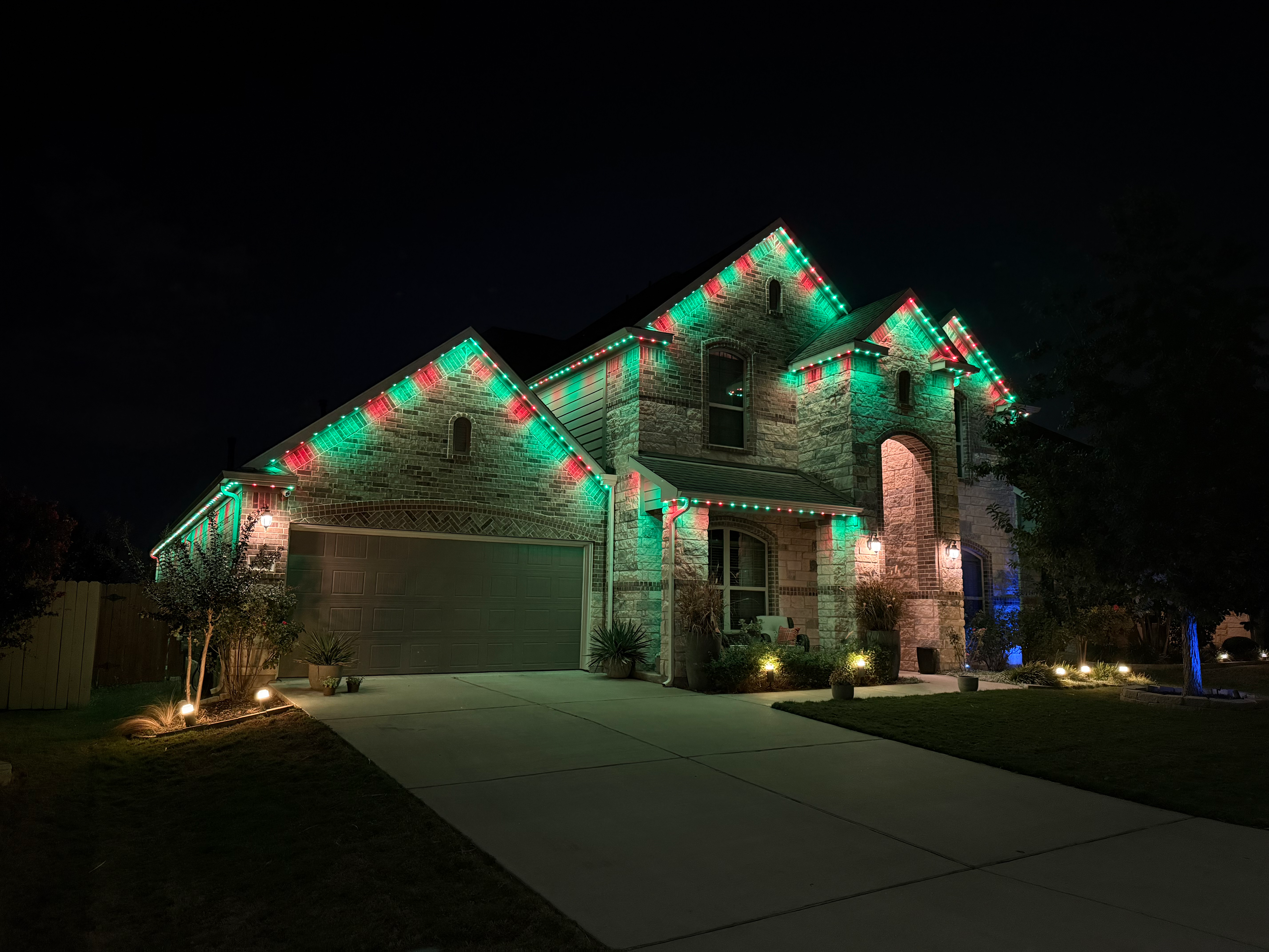 Stone home with green, white, and red holiday LED lighting