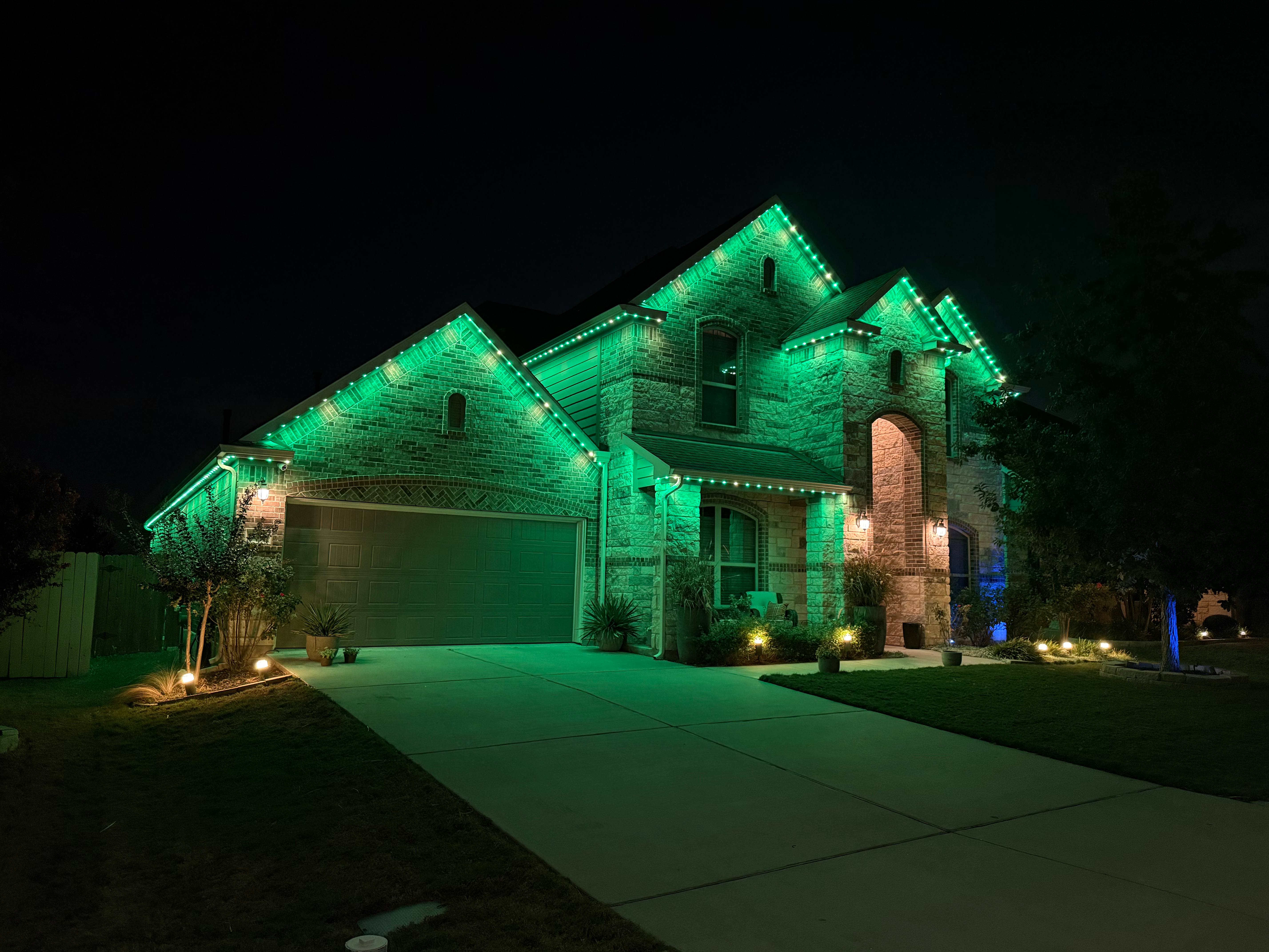 Stone home with green and white LED roofline lighting