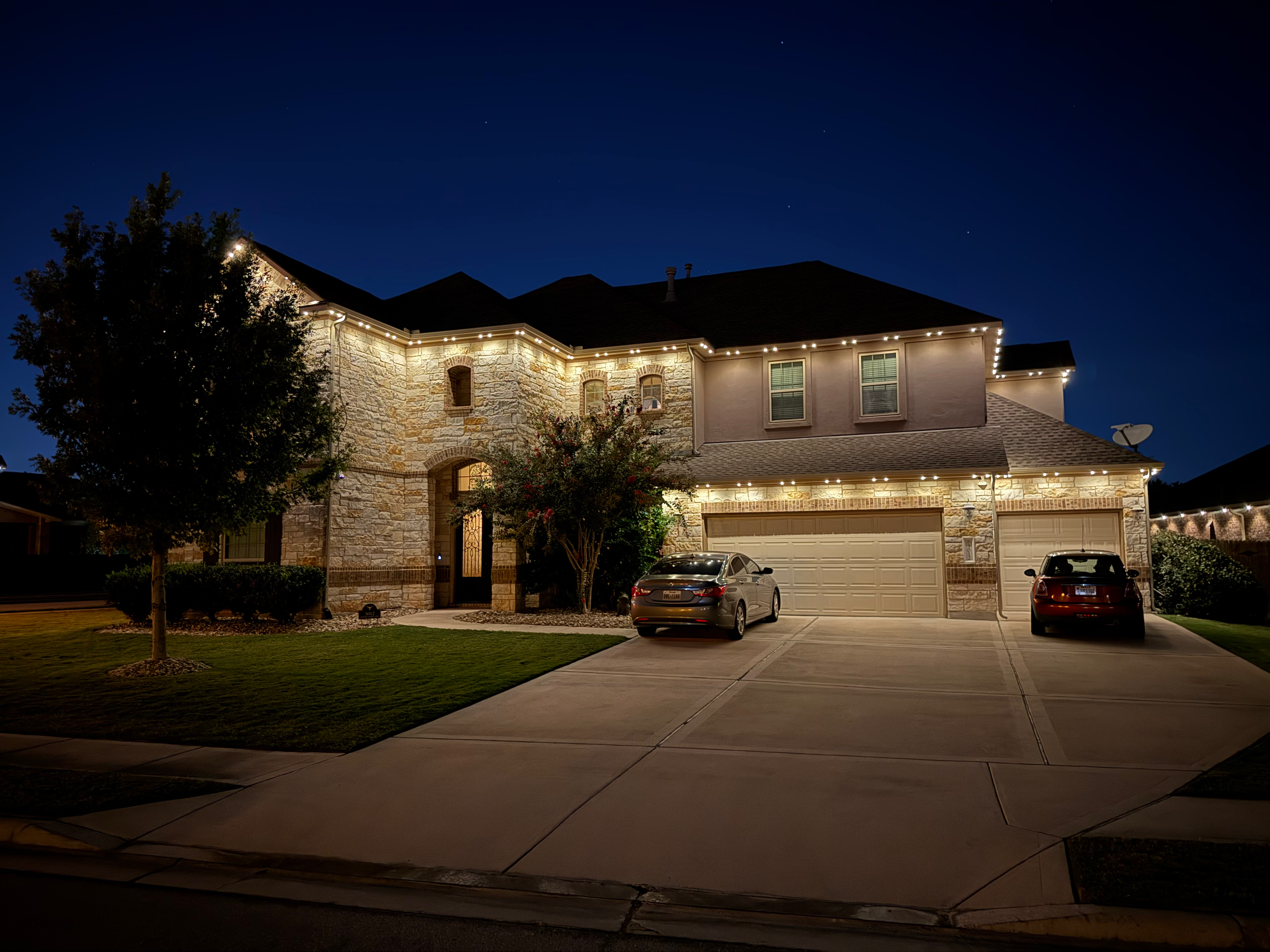 Two story stone home with full roofline and garage white LED lighting